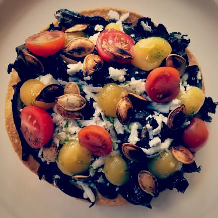 Portobello tostada topped with fresh cherry tomatoes and roasted pumpkin seeds